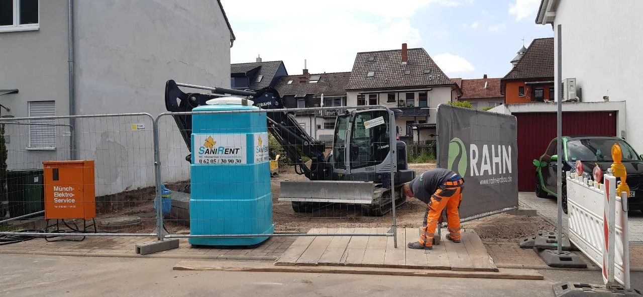 Eingerichtete Baustelle mit Bauzaun und befestigter Zufahrt auf einem Einfamilienhaus-Grundstück